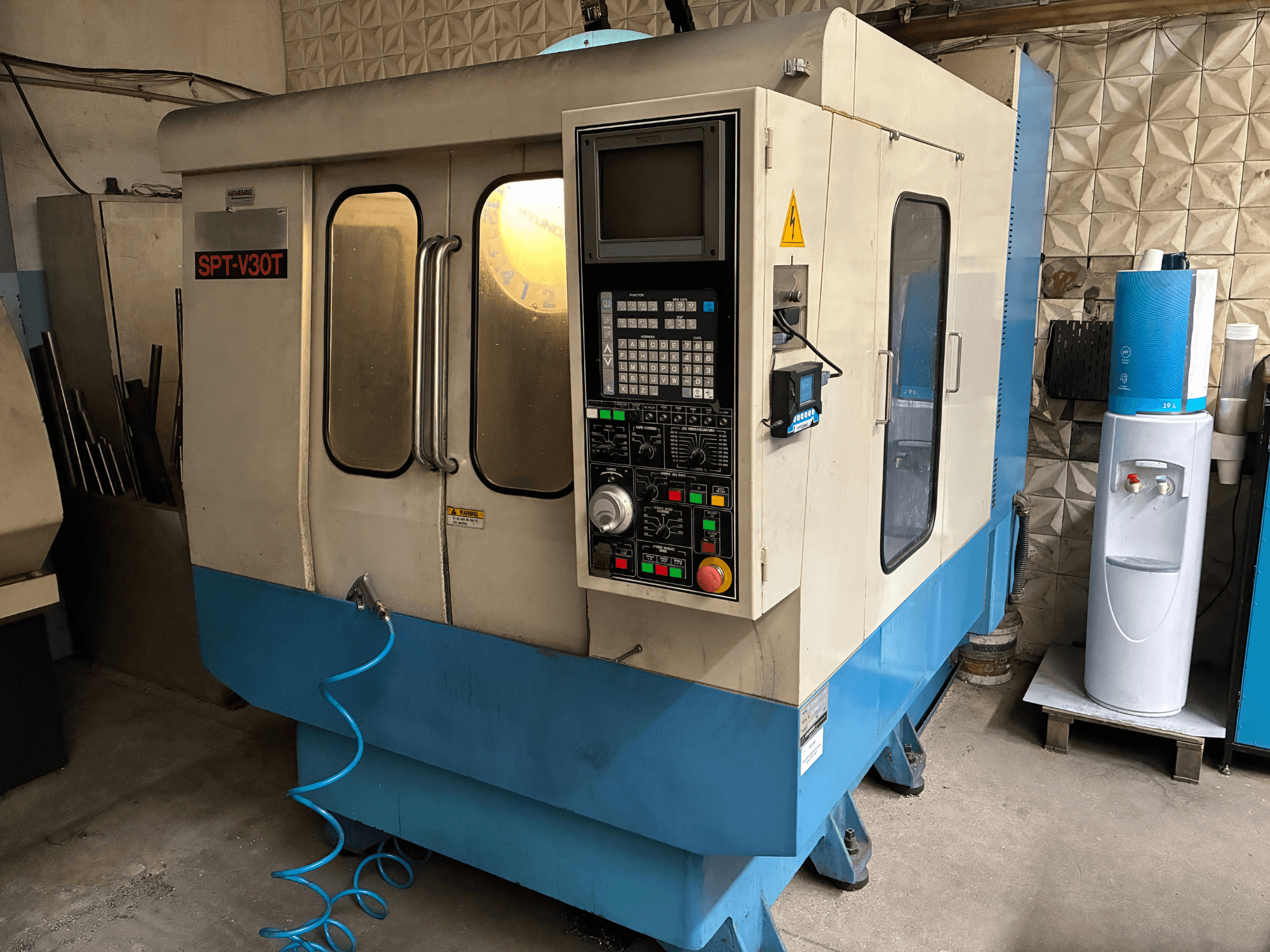 SPT-V30T milling machine in front view, featuring a control panel with buttons and a blue base, located in a workshop.